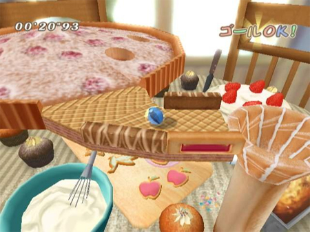 A ball rolls around a table filled with ice-cream and cake.
